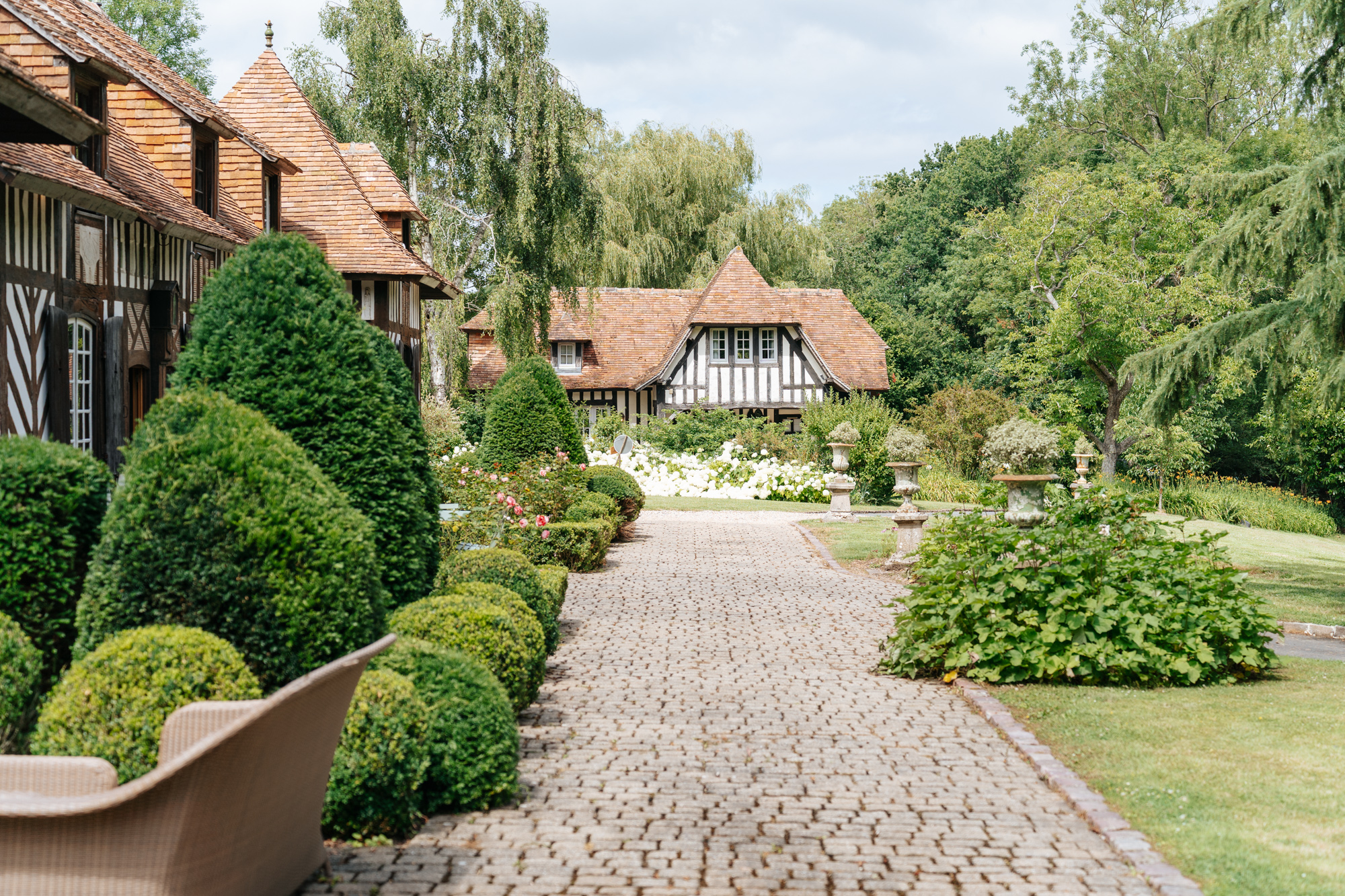 Stone pathway leading through the beautifully landscaped gardens and half-timbered houses at Domaine de Barneville.