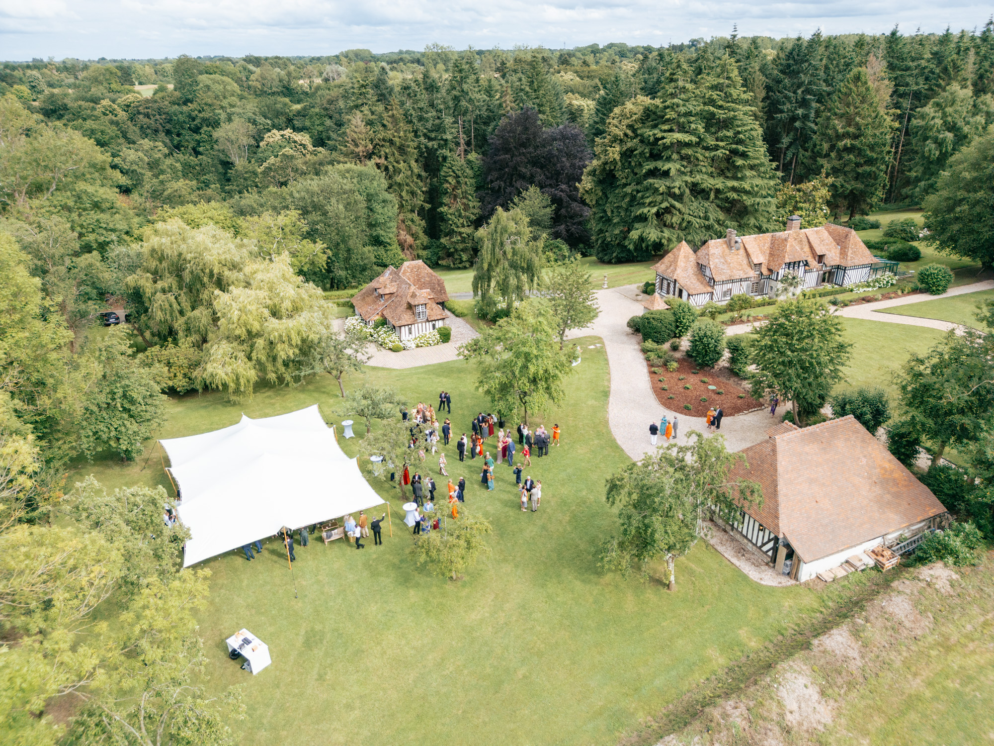 Wedding reception under a stretch tent at Domaine de Barneville, surrounded by green gardens.